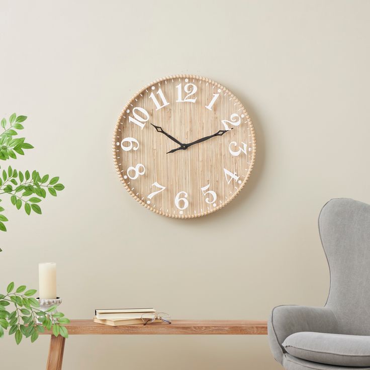 a clock on the wall next to a chair and table with a candle in it