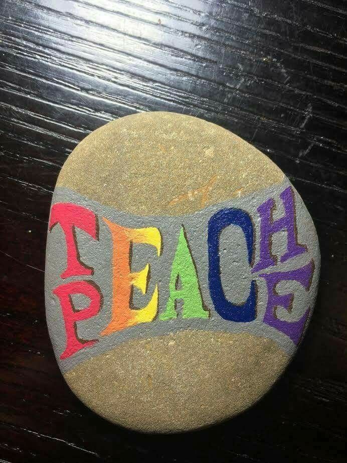 a rock with the word beach painted on it sitting on top of a wooden table