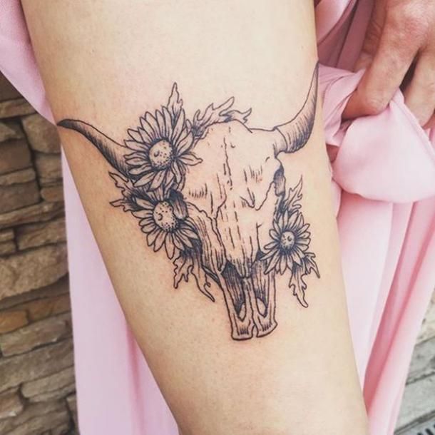 a cow skull with sunflowers on it