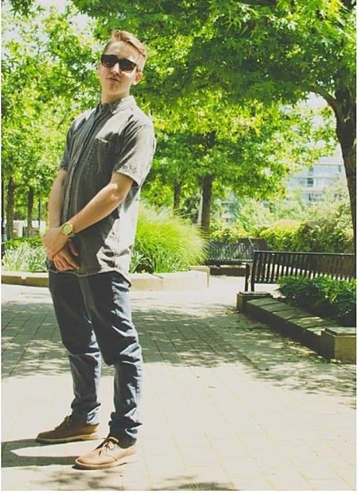 a man standing on top of a skateboard in the middle of a sidewalk next to trees