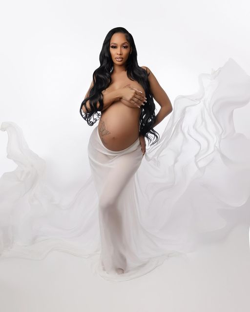 a pregnant woman posing for the camera with her hands on her hips and wearing a white dress