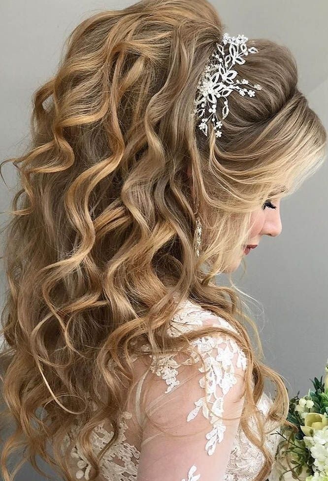 a woman with long curly hair wearing a tiara and holding a bridal bouquet