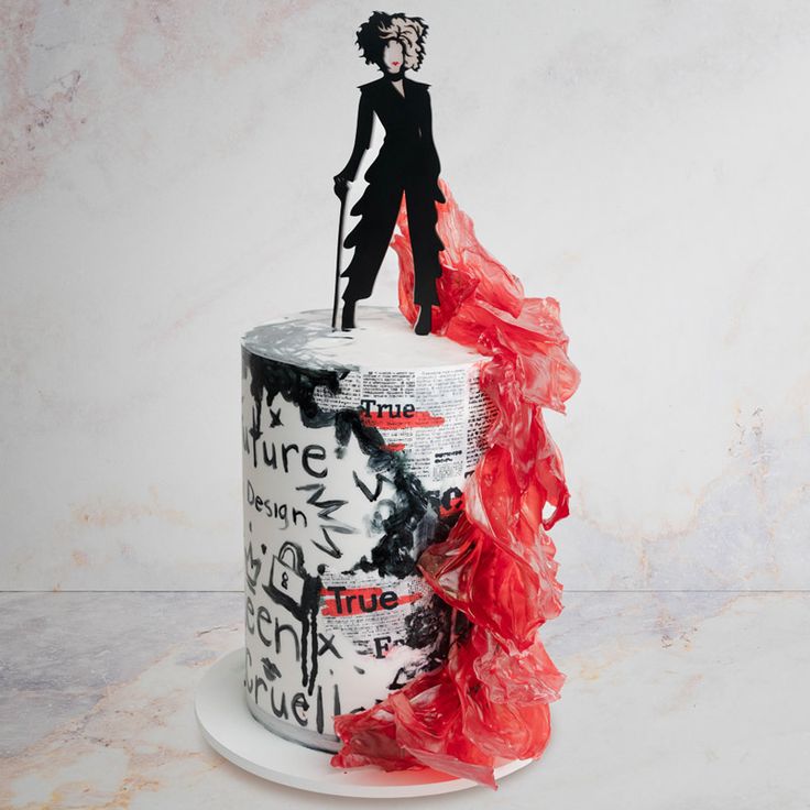 a white cake with red ruffles and a paper cutout of a woman on top