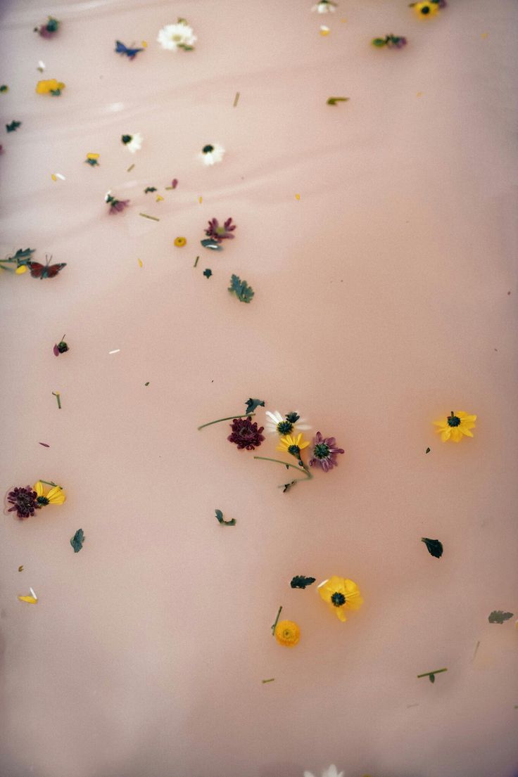 yellow and white flowers floating on top of a pink liquid filled with lots of water