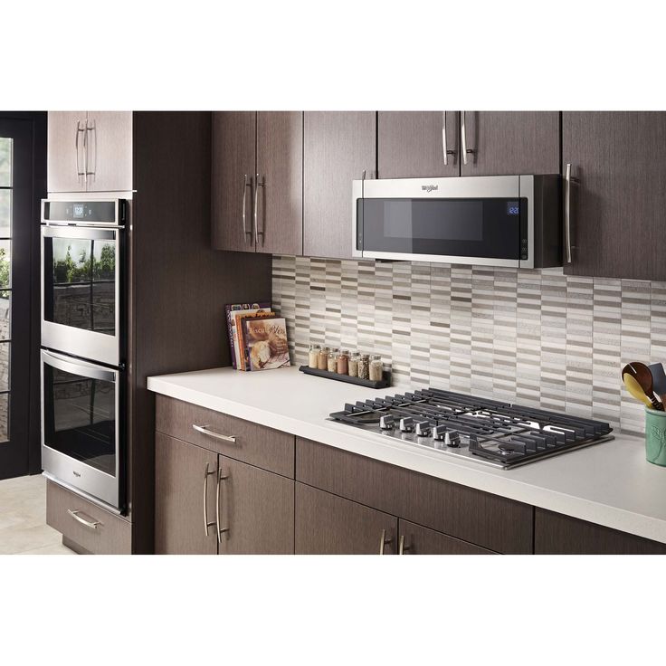 a modern kitchen with stainless steel appliances and brown cabinets