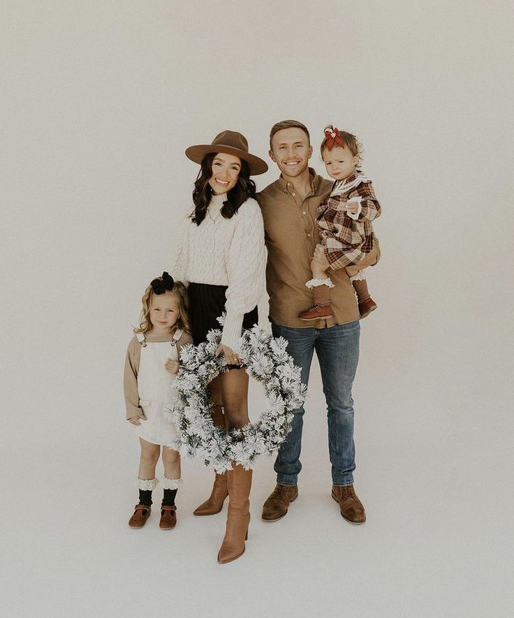 a family posing for a photo in front of a white background with wreaths and boots