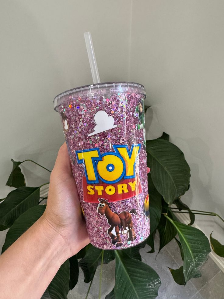 someone holding up a toy story cup with pink sprinkles on the bottom