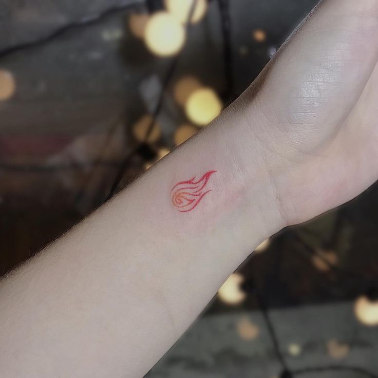 a person with a small tattoo on their left arm and wrist is holding up her hand