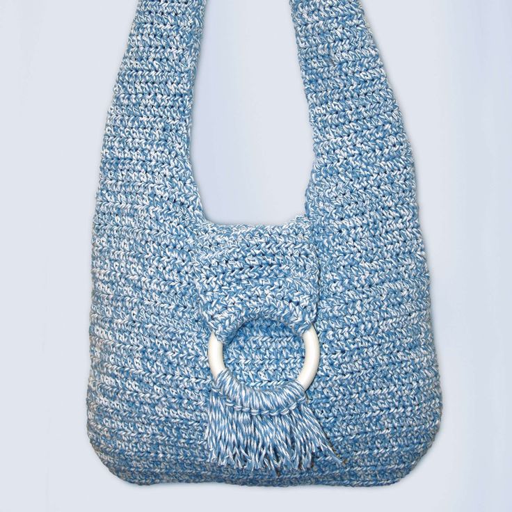 a crocheted blue purse with a white ring on the front and bottom handle