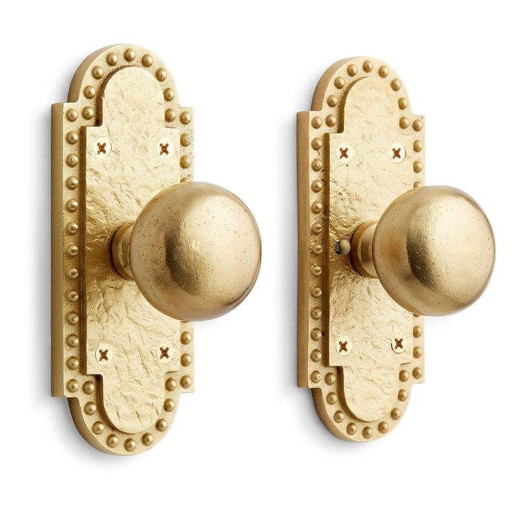 two brass door knobs with rivets on each side and an oval handle