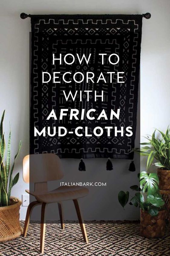 an african mud - cloth is hanging on the wall next to a chair and potted plants