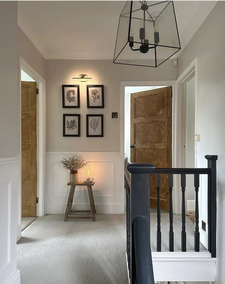 a hallway with pictures on the wall and a light fixture hanging from it's ceiling