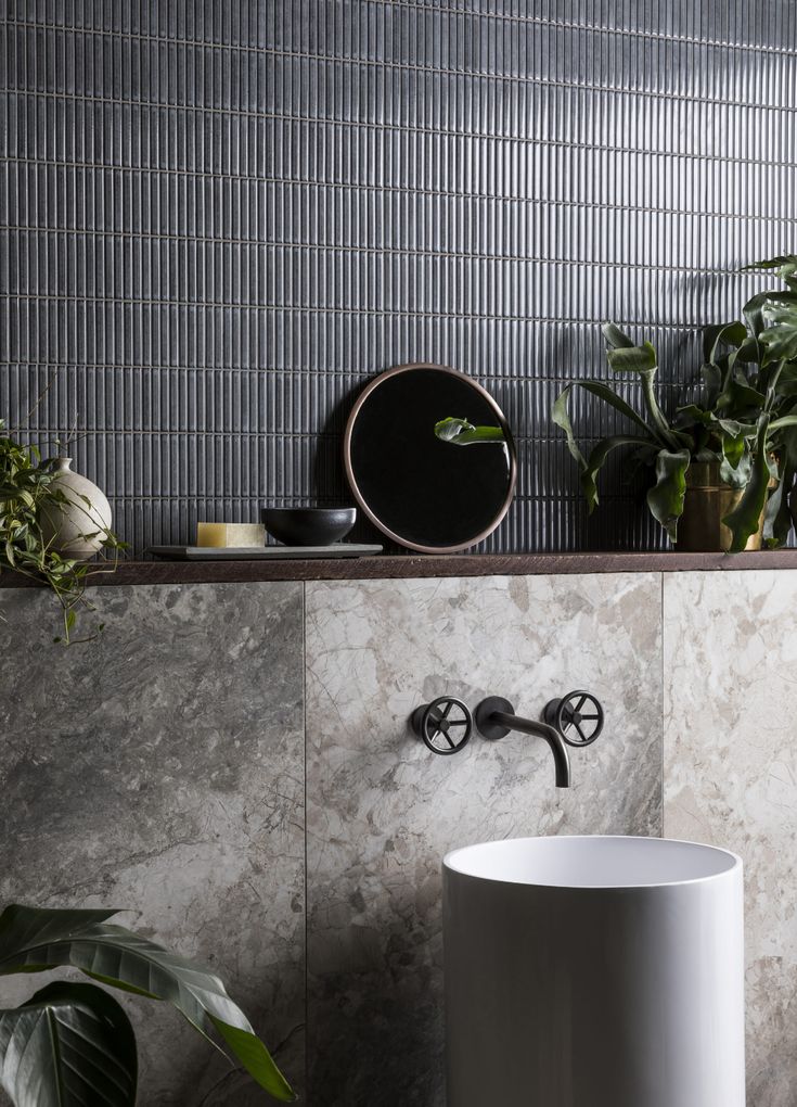 a bathroom sink sitting next to a mirror and potted plants