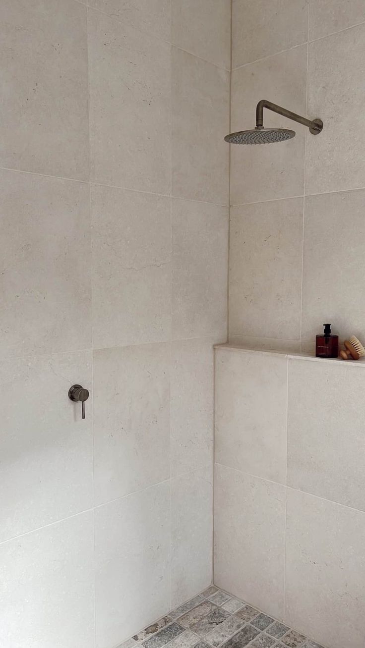 a white tiled bathroom with a shower head