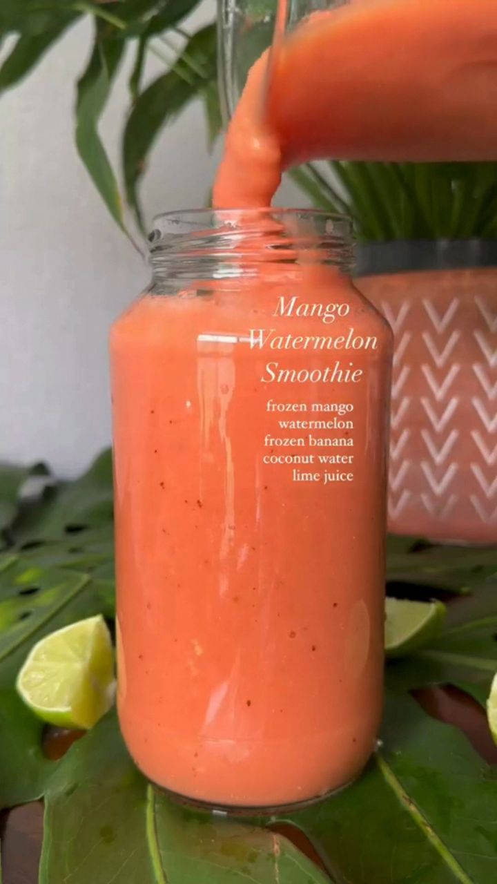 an orange smoothie is being poured into a mason jar