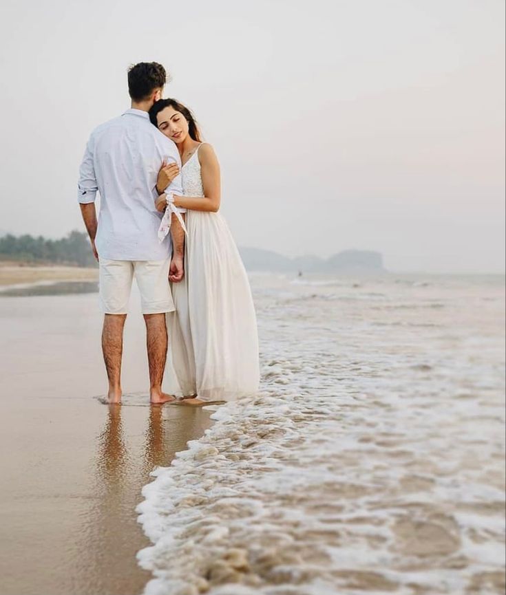 a man and woman are standing in the water at the beach