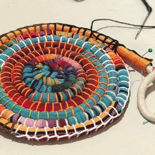 a close up of a colorful woven object on a table next to a pair of scissors