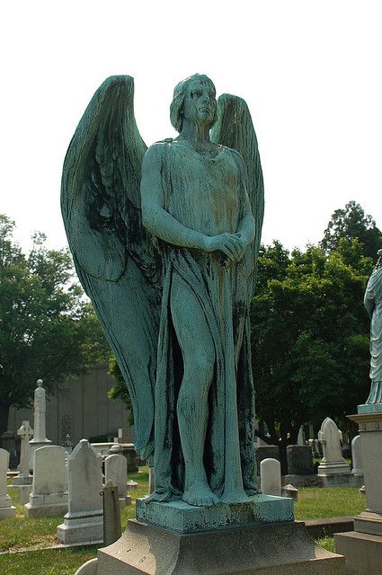 an angel statue is standing in the middle of a cemetery