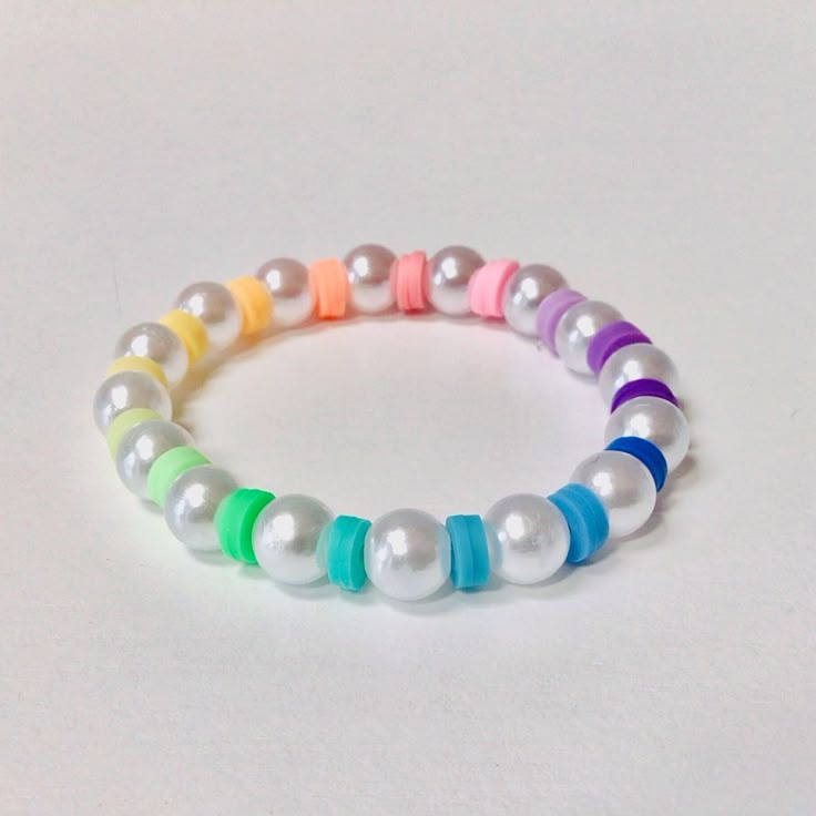 This is a clay bead stretch bracelet. This clay bead bracelet has rainbow clay beads along with white pearls. Clay Bead Bracelet Ideas Rainbow, Clay Bead Bracelet Ideas No White, Bracelet Ideas With Clay Beads, Bracelet Clay Beads Ideas, Macaroni Bracelet, Bracelets Ideas Beaded, Bracelet Buisness, Clay Beads Bracelet Ideas, Clay Bead Jewelry