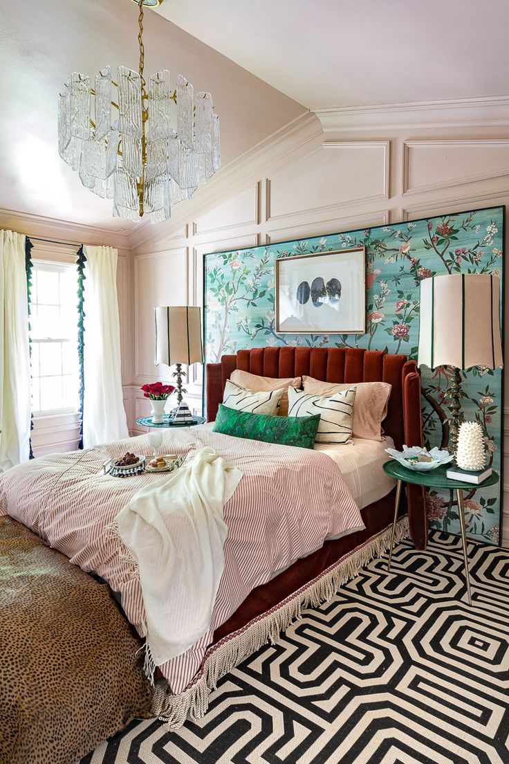 a bedroom with a bed, chandelier and rugs on the floor in front of a window