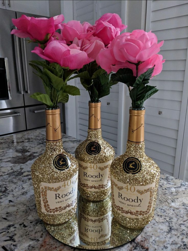 three bottles with roses in them sitting on a marble counter top next to each other