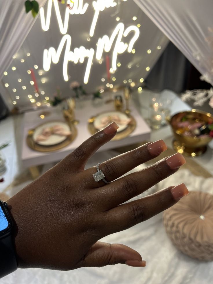 a person's hand with a ring on it near a cake and other decorations