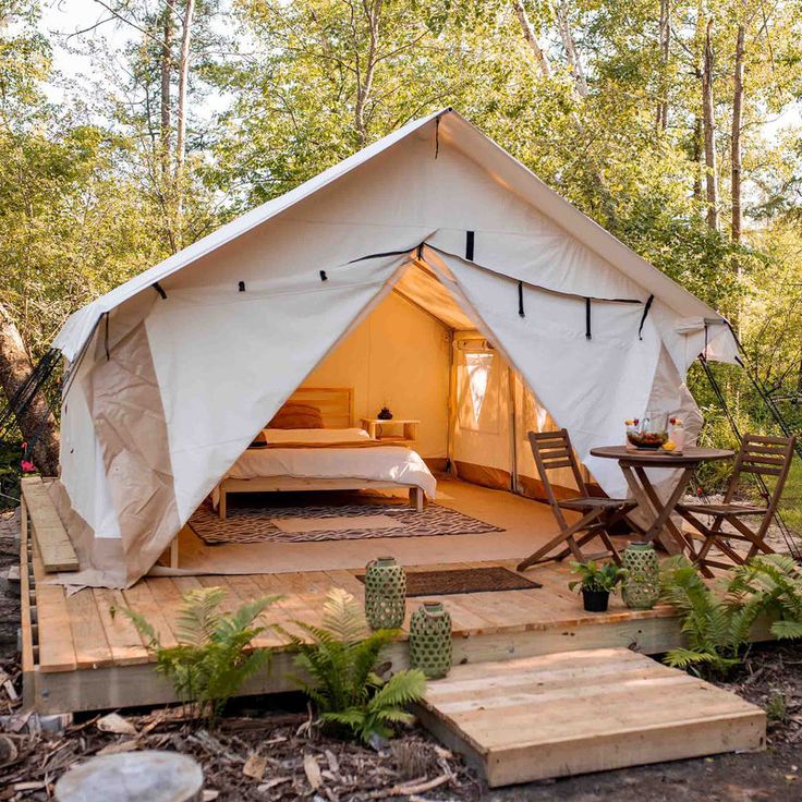 a tent in the woods with stairs leading up to it and a bed sitting inside