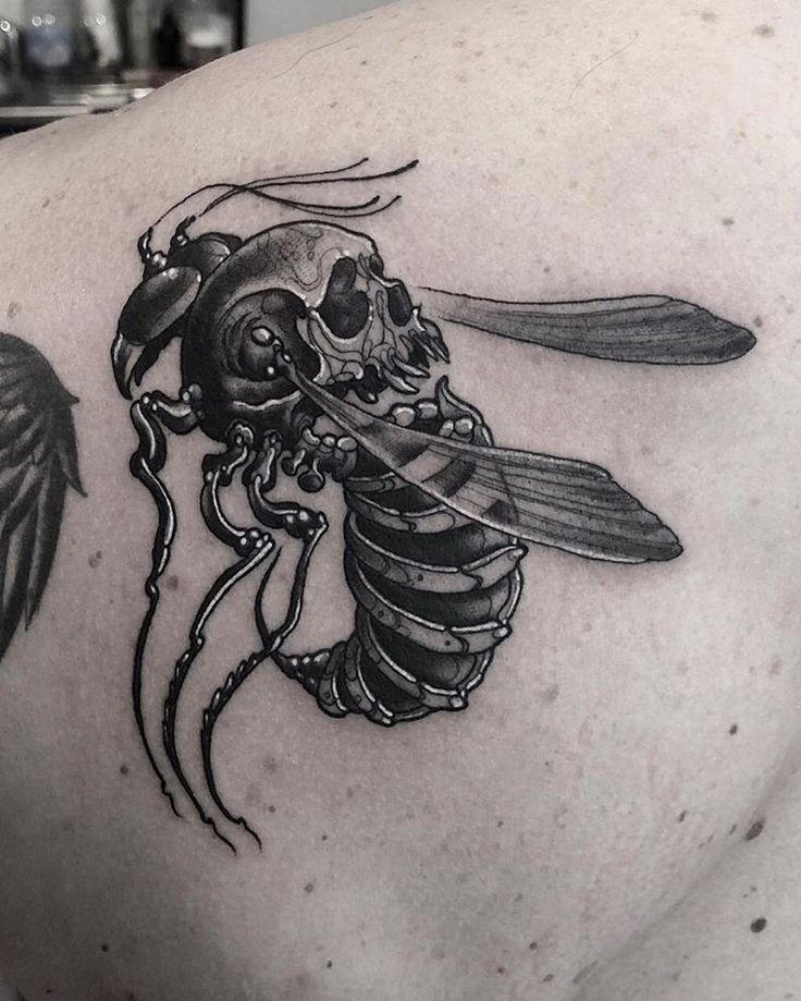 a man's back with a skull and a bee tattoo on it