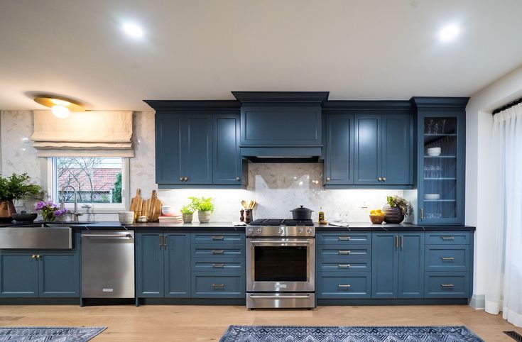 a kitchen with blue cabinets and stainless steel appliances