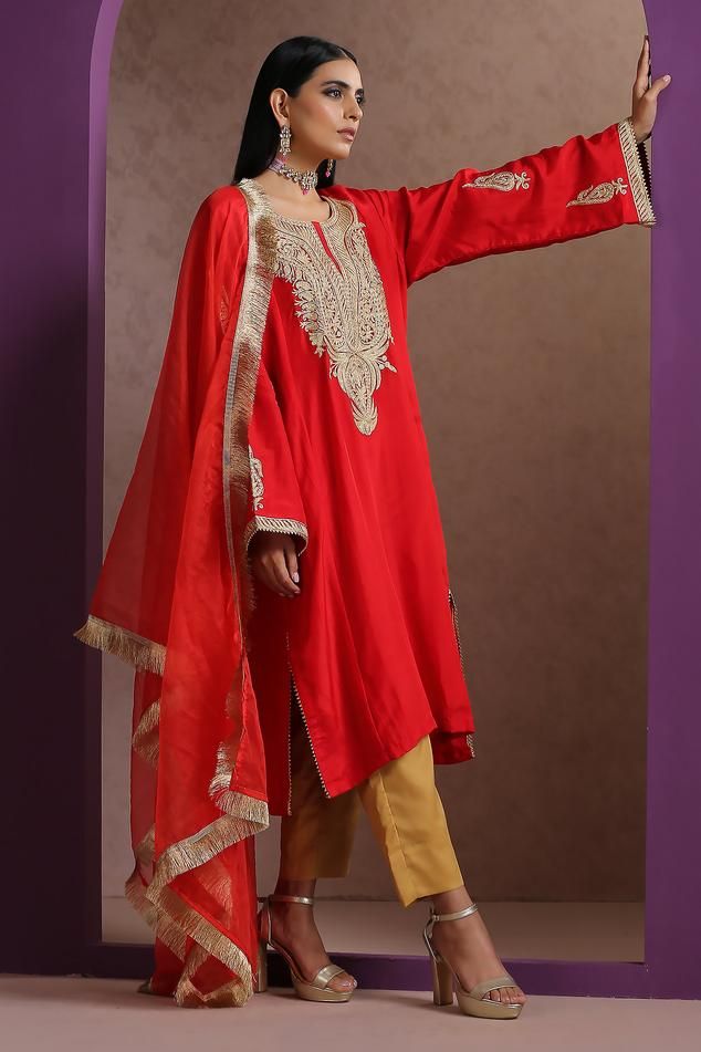 Red pheran with gold Kashmiri tilla embroidery in floral pattern on yoke. Paired with pant and fringe lace bordered dupatta.
Components: 3
Pattern: Embroidery
Type Of Work: Kashmiri Tilla
Neckline: Round
Sleeve Type: Full sleeves
Fabric: Silk, Crepe, Organza, Lining: Cotton
Color: Red
Other Details: 
Contrast pant
Side pockets on kurta
Fringe lace bordered dupatta
Approx. weight: 1 kgs
Length:
Kurta: 42 inches
Pant: 38 inches
Model height: 5ft 7inches, wearing size S
Occasion: Mehendi and Haldi Red Unstitched Designer Wear Dupatta, Designer Red Unstitched Dupatta, Unstitched Gold Embroidered Georgette Dupatta, Unstitched Festive Churidar With Gold Embroidery, Unstitched Georgette Dupatta With Gold Embroidery, Bollywood Style Georgette Traditional Wear With Gold Embroidery, Bollywood Traditional Wear In Georgette With Gold Embroidery, Eid Dupatta With Gold Embroidery In Georgette, Elegant Red Raw Silk Salwar Kameez