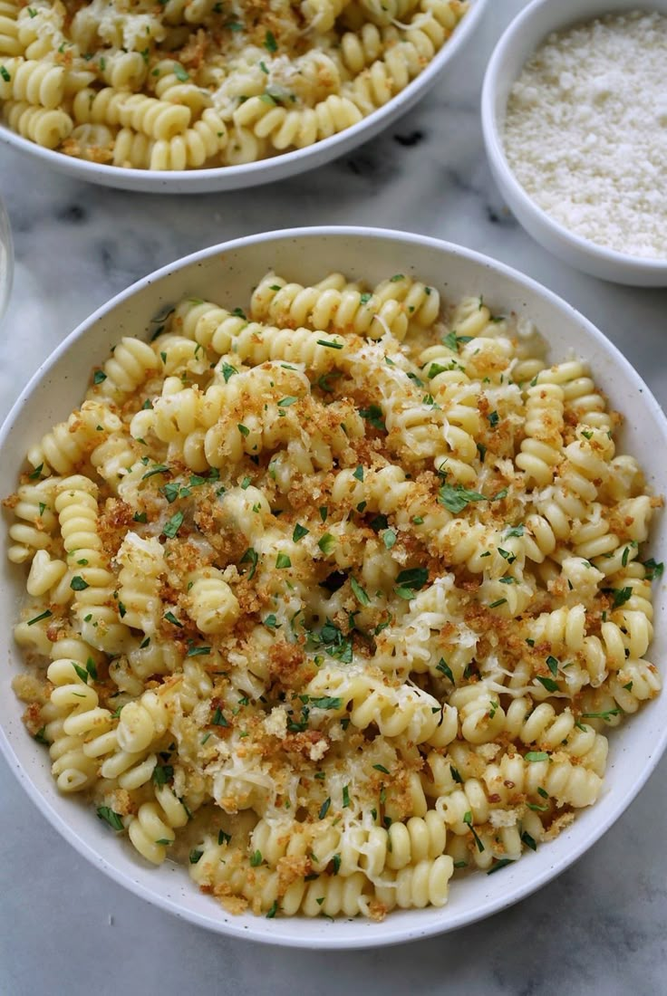 two bowls filled with macaroni and cheese on top of a marble countertop