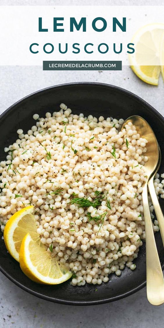 lemon couscous in a black bowl with spoons and lemon slices on the side