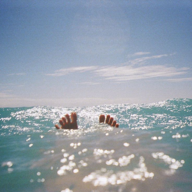 someone's feet sticking out of the water on a sunny day in the ocean