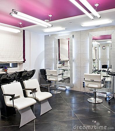 the interior of a salon with chairs, mirrors and lights on the ceiling in front of them