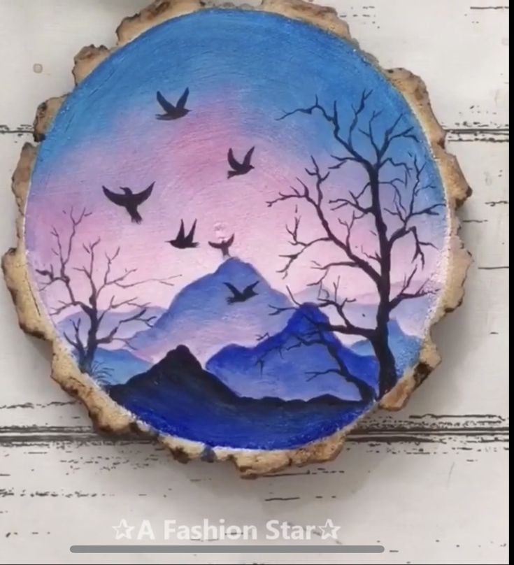 a painting on a piece of wood with trees and birds flying in the sky above it