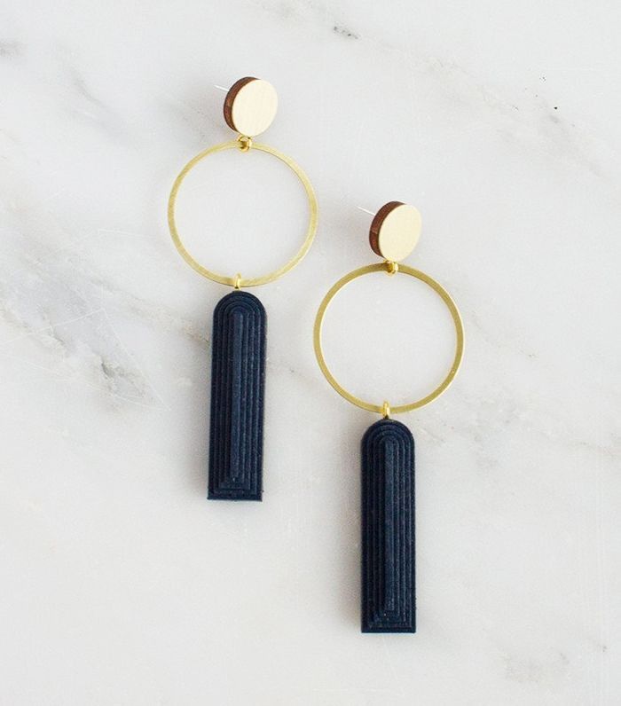 the gold and black hoop earrings are on top of a marble surface with two circles, one