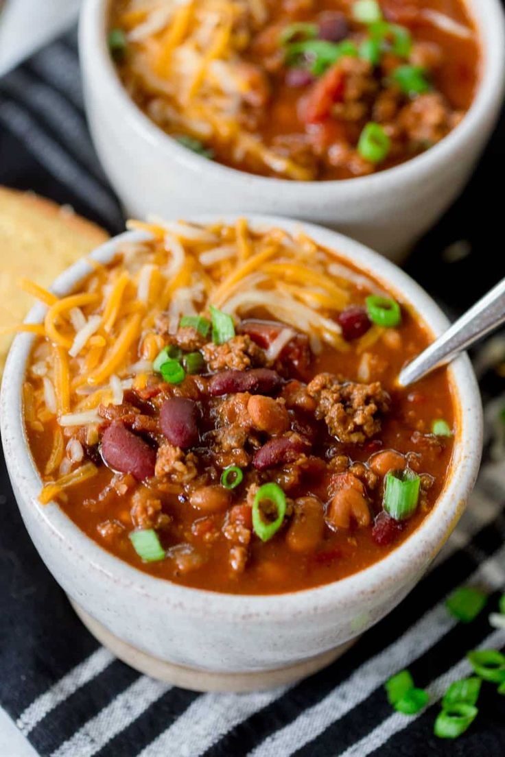 a white bowl filled with chili and cheese on top of a black and white towel