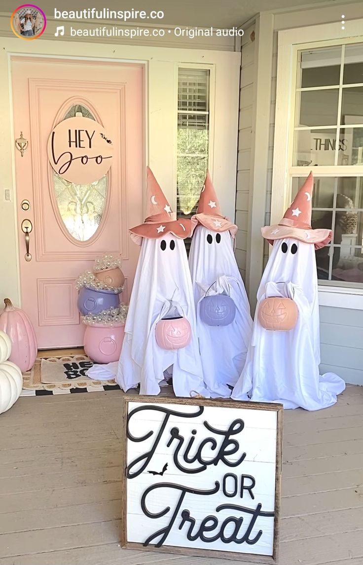 three ghost statues are standing in front of a trick or treat sign on the porch