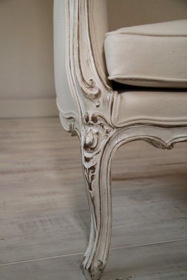 an old white chair sitting on top of a hard wood floor