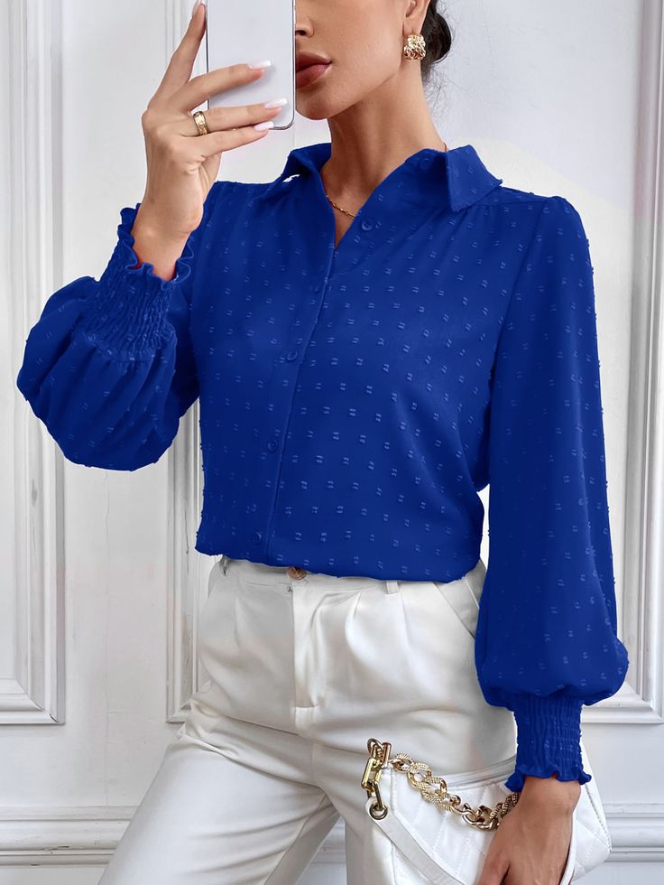 a woman in white pants and a blue shirt taking a selfie with her cell phone