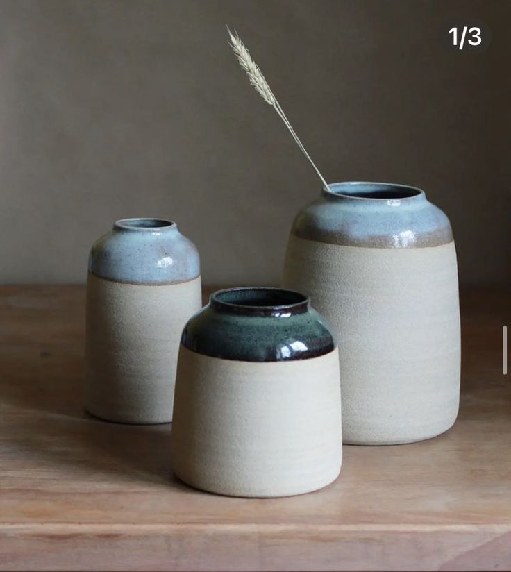 two white and blue vases sitting on top of a wooden table next to each other