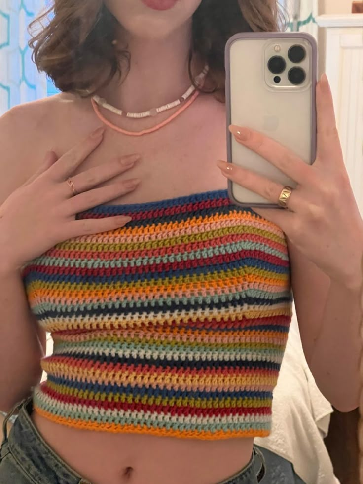 a woman taking a selfie with her cell phone and wearing a crocheted crop top