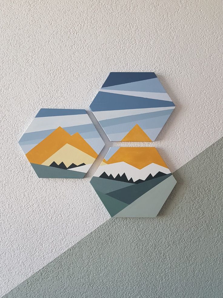 three hexagons are hanging on the wall with mountains painted on them in different colors