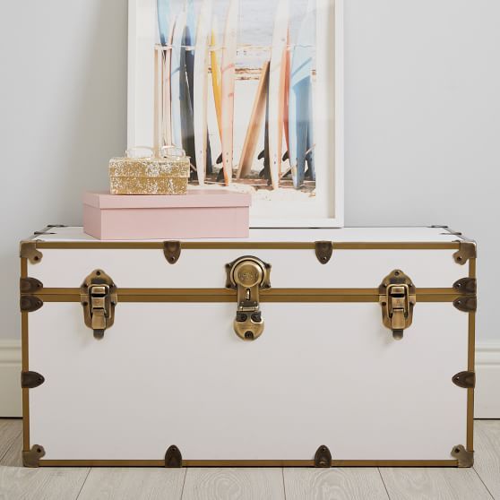 a white trunk sitting on top of a hard wood floor next to a framed photo