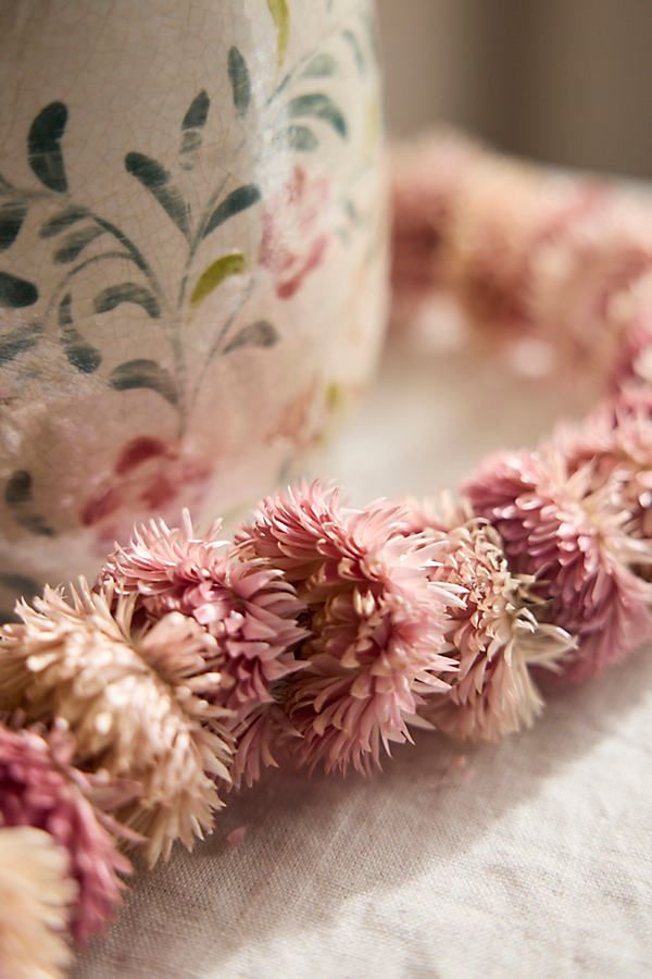 some pink flowers on a table next to a cup