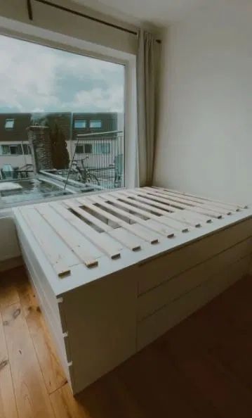 there is a bed that has been made out of pallet wood and sits in front of a window