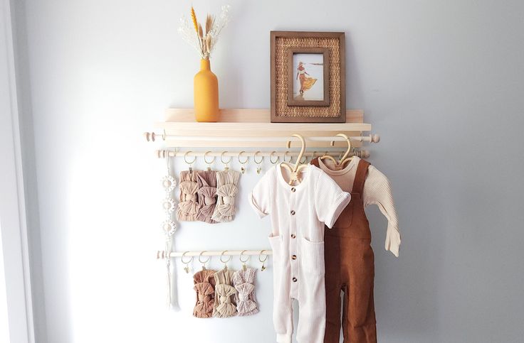 there is a baby's clothes hanging on the wall next to a framed picture