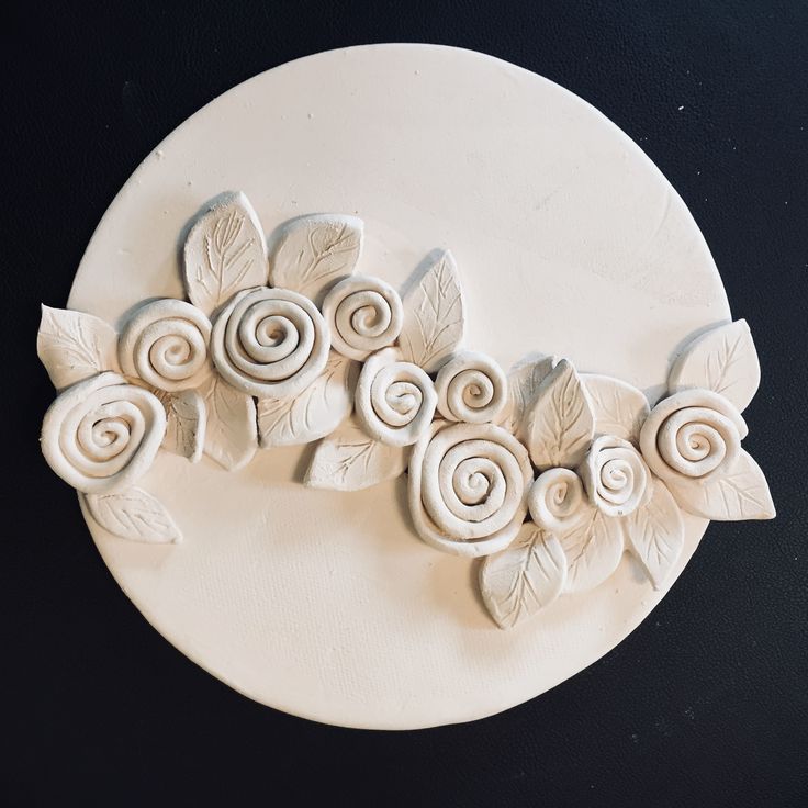 a white plate topped with flowers and leaves on top of a black tableclothed surface