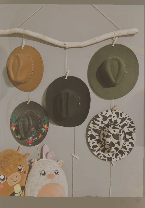 several hats are hanging on the wall with animal faces and other things attached to them