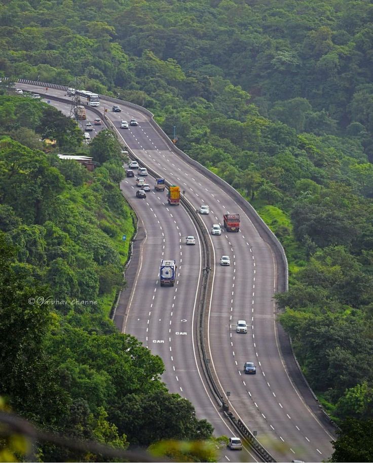 an aerial view of a highway with cars driving on it and trees in the background